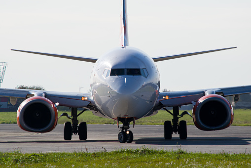 Face-to-face close-up photo of a passenger commercial aircraft turning around on the runway before takeoff