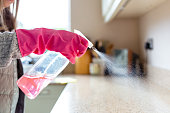 Woman spraying surface cleaner on kitchen countertop