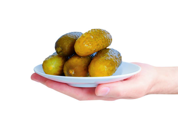 Close-up view of a white saucer with pickled cucumbers in hand on white.
