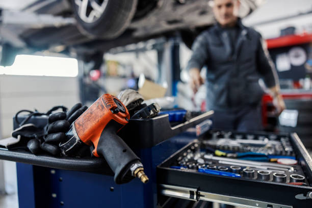 istock Close up of a drill on a mechanic toolbox with tools with worker reaching for tools in blurry background at mechanic's shop. 1939640923