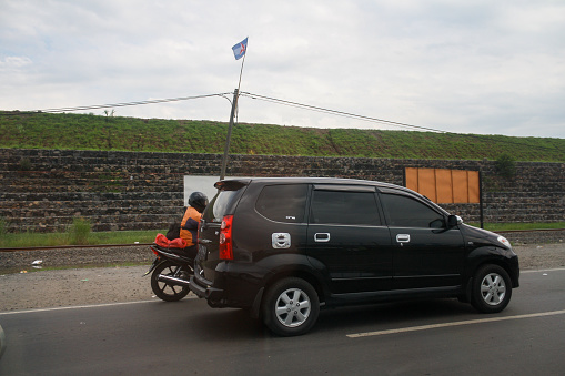 Sidoarjo, Indonesia - Dec 2011: View of car and motorcycle on road at mud volcano disaster with cloudy sky background.