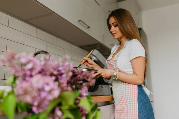 beautiful woman standing in kitchen with apron - stereotypical housewife women domestic kitchen brown hair ストックフォトと画像