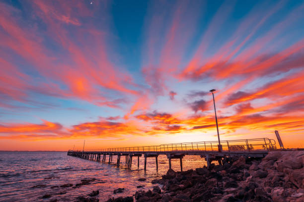 Robe jetty with fishermen during sunrise while viewed from the shore, Limestone Coast, South Australia