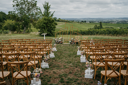 Chairs in a row set up for a beautiful wedding ceremony on a meadow outdoors in nature.