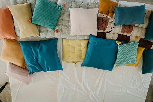 Bunch of different color pillows on a bed in apartment.