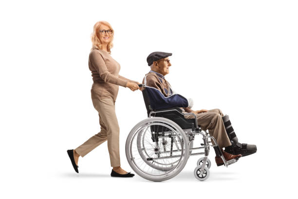 middle aged woman pushing a senior with a broken arm in a wheelchair - physical injury men orthopedic equipment isolated on white imagens e fotografias de stock