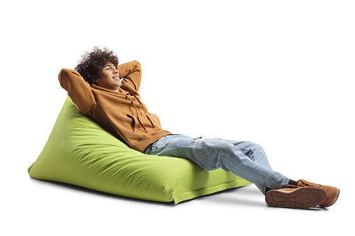 Generation z guy resting on a green bean bag armchair isolated on white background