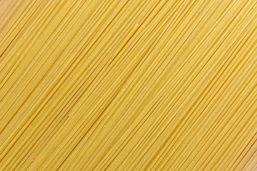 Yellow long spaghetti on a rustic background. Yellow italian pasta. Long spaghetti. Raw spaghetti bolognese. Italian food and menu concept.