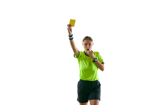 Serious woman, soccer referee gesturing, raising hand, stopping game and showing yellow card as warning against white studio background. Concept of sport, competition, match, profession, football game