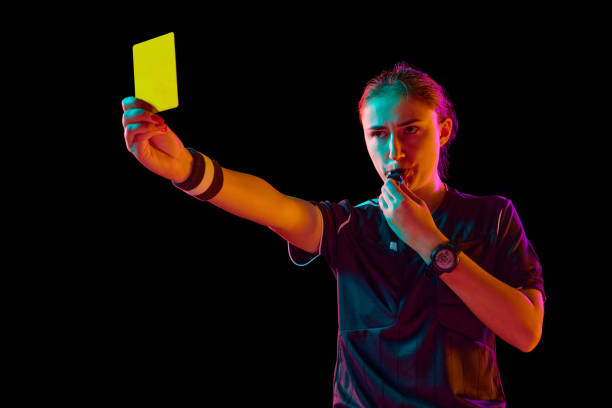 istock Disciplinary action. Female referee showing yellow card against black studio background in neon light. Following game rules 1939710580