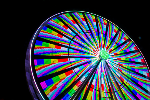 Experience the mesmerizing spectacle of a vibrant Ferris wheel at night in Gatlinburg, Tennessee. This long-exposure image captures the wheel's colorful light patterns, creating a dynamic and psychedelic display.