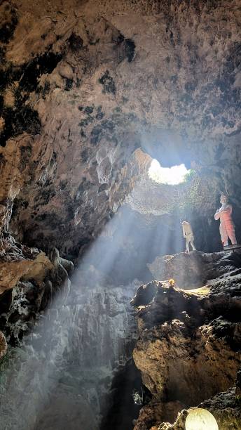 istock Low angle view of cave with hole above. View from inside the jatijajar cave, Central Java, Indonesia. Sunlight enters the cave. Statue decorations that tell ancient legends. 1939718920