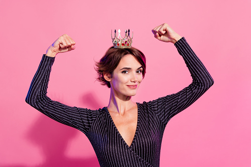 Photo of funky lucky lady wear glamour outfit crown rising fists showing biceps isolated pink color background.