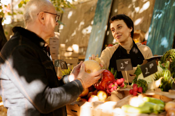 istock Vendor offers fresh squash to client 1939731496