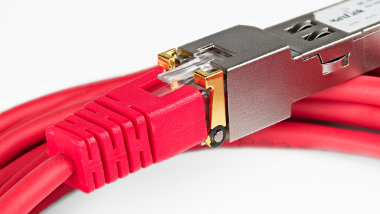 Closeup of standardized small form-factor pluggable (SFP) transceiver and red Ethernet twisted pair patch cables