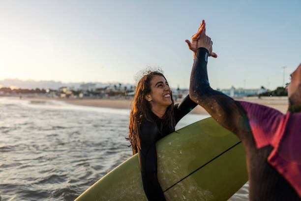 istock Happy surfers giving high five while standing in water. 1939745964