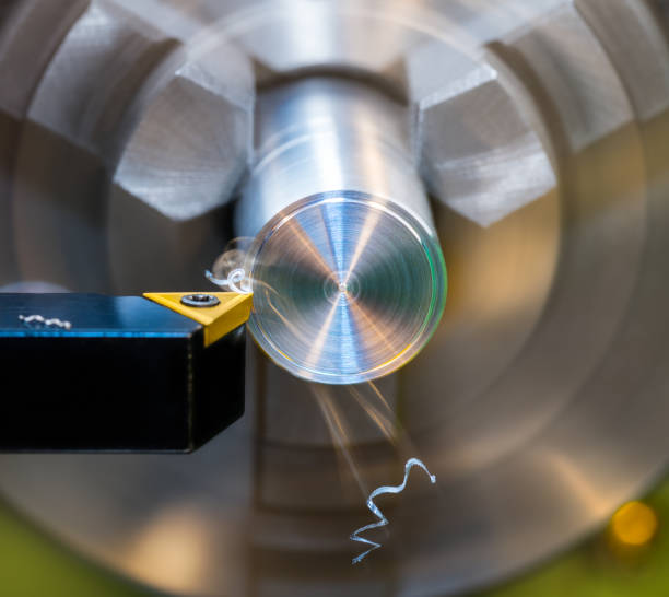 Closeup a black tool bit with sharp cutting edge on yellow carbide insert at turning