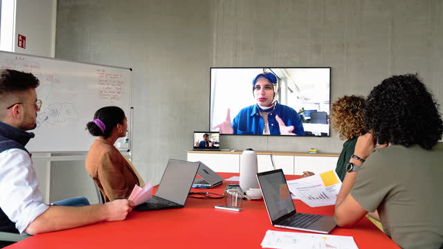 Islamic woman entrepreneur having video conference meeting with team in office