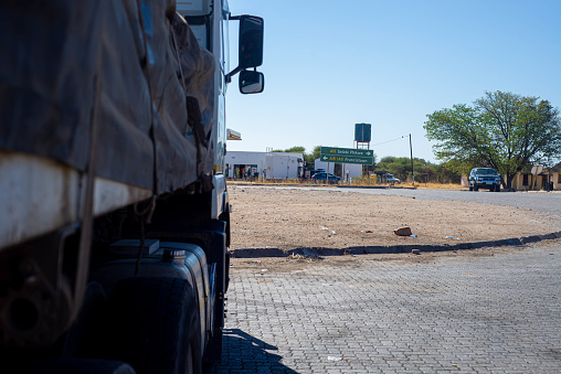A long haul truck carrying cargo is parked facing the road in Botswana on a warm clear sky day