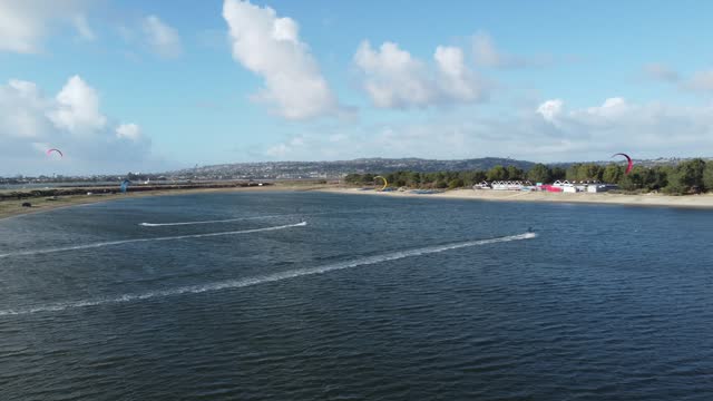 Aerial Tracking Shot Of Kite Surfers Racing Across Fiesta Island Park In Mission Bay, San Diego; Popular Attractions.