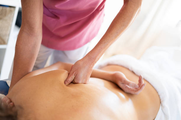 istock Crop masseuse massaging shoulder of client lying face down 1939792374