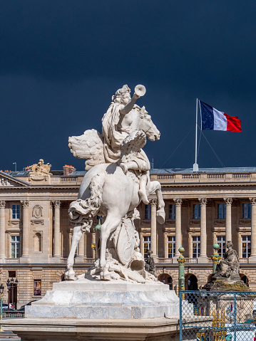 View of a government building in Paris with the French flag. An equestrian figure in the foreground.