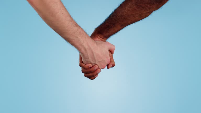 Gay holding hands, diversity and closeup with partner, help and support with love and relationship on blue background, Men together, wellness and lgbt trust, care and bonding with kindness in studio