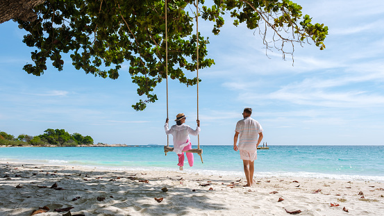 Child on swing. Kid swinging on tropical beach. Travel with young children. Summer family vacation on exotic island. Kids play on sea shore. Little girl playing in luxury resort.