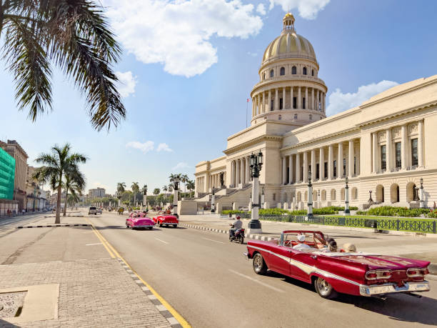 Vista della strada di un'auto decappottabile che guida davanti all'edificio El Capitolio - foto stock