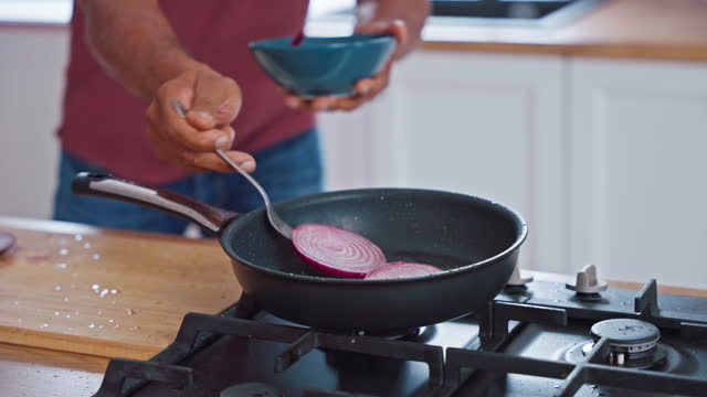 Sliced Red Onions Being Put on a Hot Frying Pan