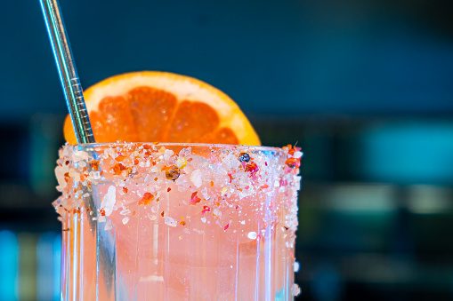 A refreshing beverage is placed on a table with a straw and garnished with a slice of juicy orange