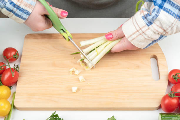 istock Female hands cut green onions with kitchen scissors. 1939864447