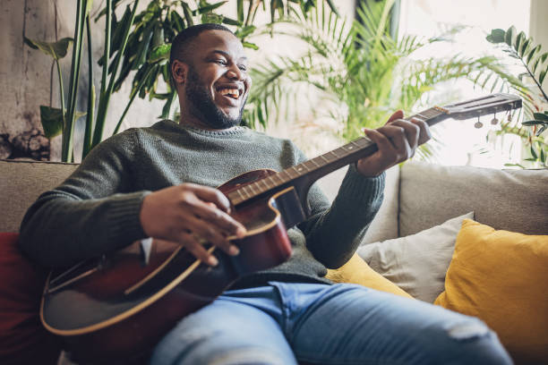 istock Joyful Man Playing Guitar at Home 1939886363