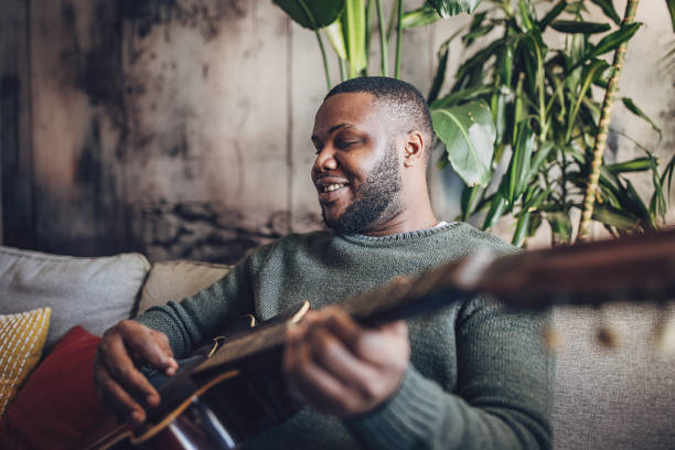 istock Joyful Man Playing Guitar at Home 1939886979