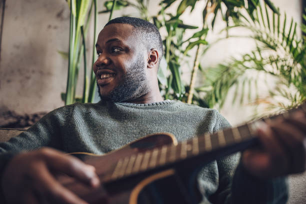 istock Joyful Man Playing Guitar at Home 1939888100