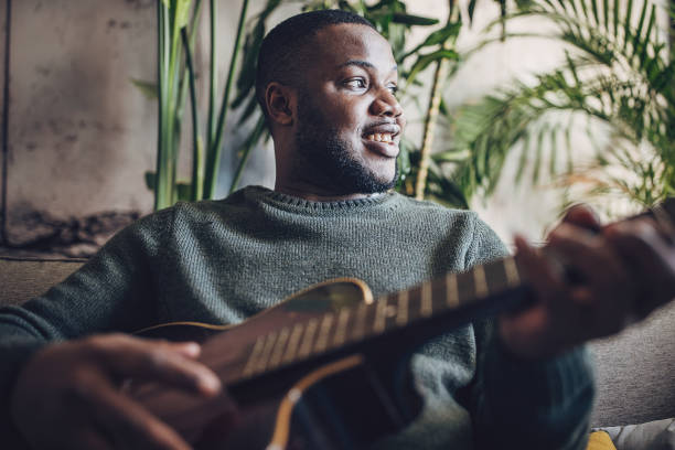 istock Joyful Man Playing Guitar at Home 1939888793