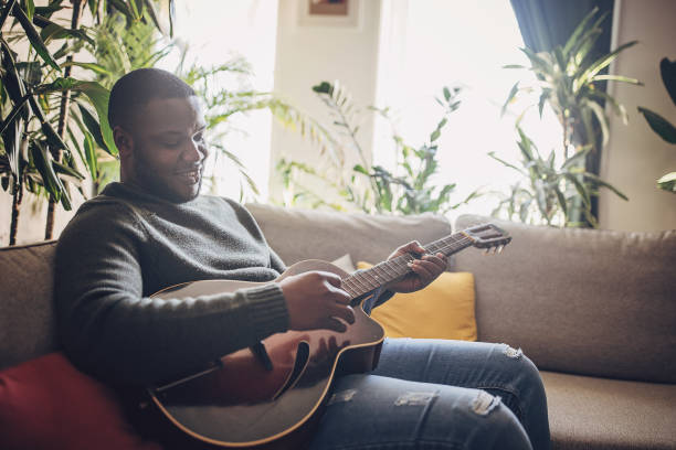 istock Joyful Man Playing Guitar at Home 1939889938