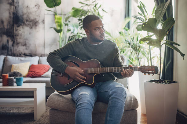 istock Joyful Man Playing Guitar at Home 1939890579
