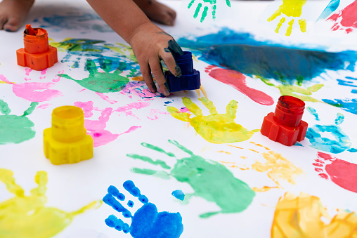 Multi coloured palm of hand of child on a white paper. Painting activity, creativity and fun for children. Handprint backgrounds.