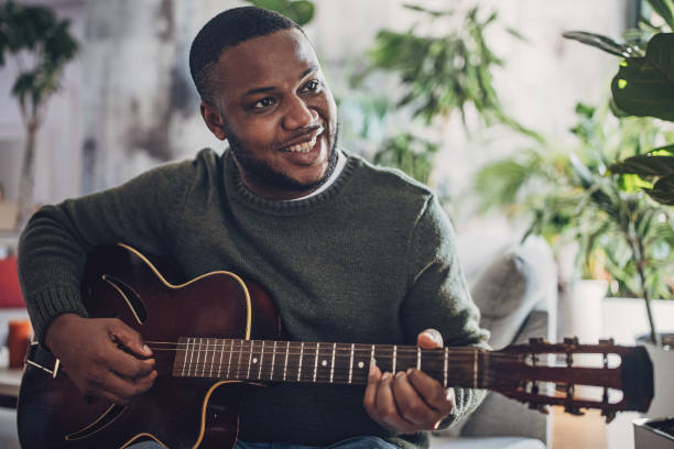 istock Joyful Man Playing Guitar at Home 1939891200