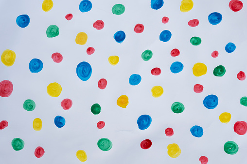 Painting of child - multi coloured dots on white background. Fun play and craft as a hobbies. Multi-coloured background. Overhead view.