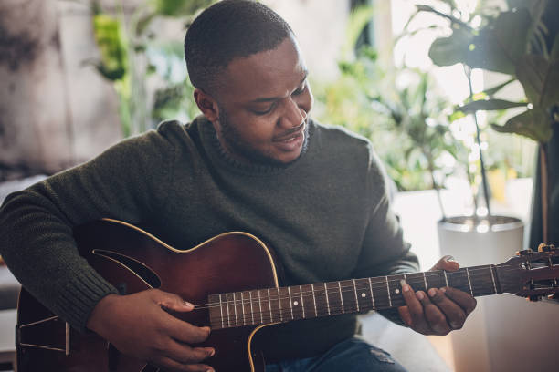 istock Joyful Man Playing Guitar at Home 1939893348