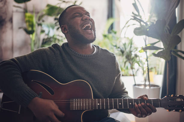 istock Joyful Man Playing Guitar at Home 1939894423