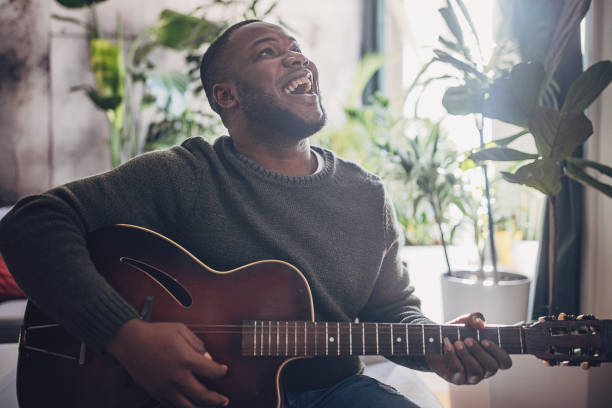 istock Joyful Man Playing Guitar at Home 1939894986