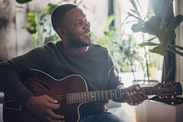istock Joyful Man Playing Guitar at Home 1939896095
