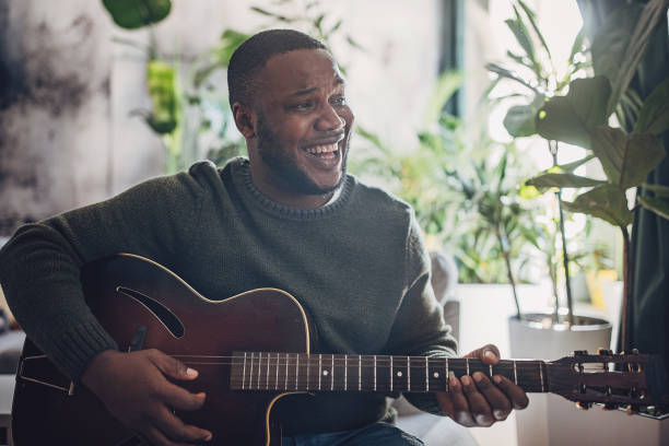 istock Joyful Man Playing Guitar at Home 1939897148