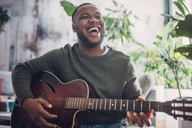 istock Joyful Man Playing Guitar at Home 1939898213