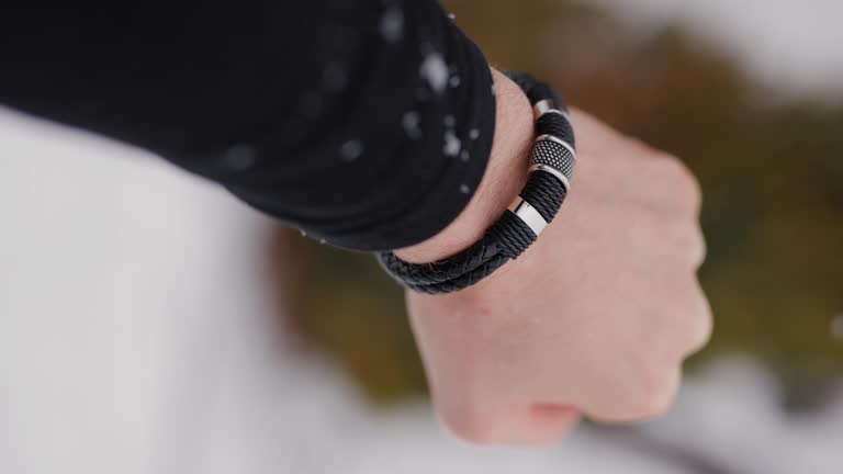 Black leather bracelet on a male hand in snow, vertical video