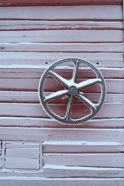 Frosty cartwheel on the wall of a frozen red cabin in Lapland, Finland. Details of a frozen abandoned cottage in the nordics. No people.