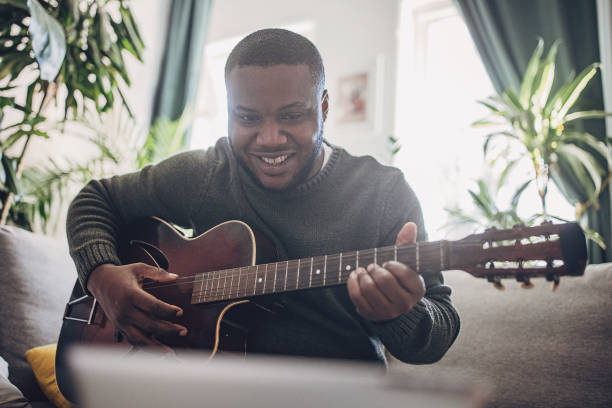 istock Joyful Man Playing Guitar at Home 1939904645